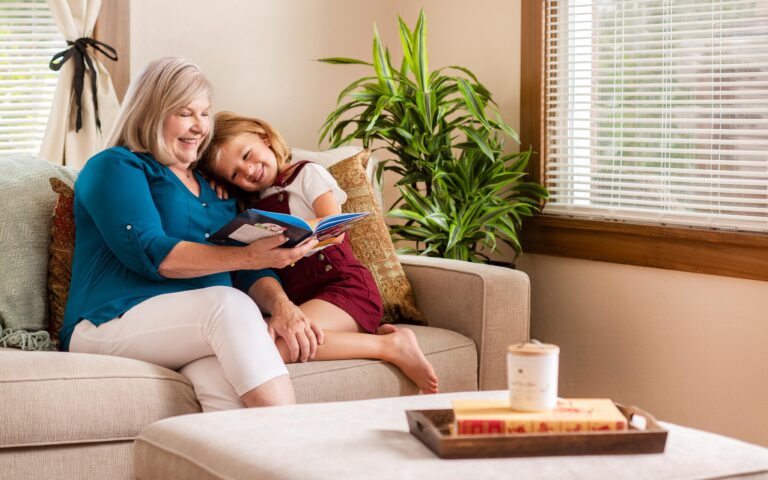 Senior Care Plus Insured Grandmother with grandchild on a sofa reading book